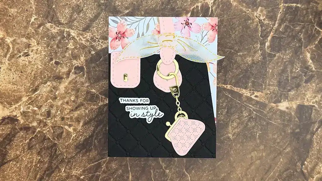 A Spellbinders greeting card featuring a purse and keychain design, floral pattern at the top, and the text "Thanks for showing up in style" on a marble surface—perfect for your Nov 2025 Kits or cardmaking projects.