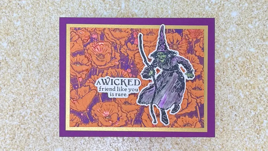 A handmade card with a purple border, orange floral background, a witch illustration, and the text "A wicked friend like you is rare. This card was created using products from Spellbinders Wonder of Oz Collection.
