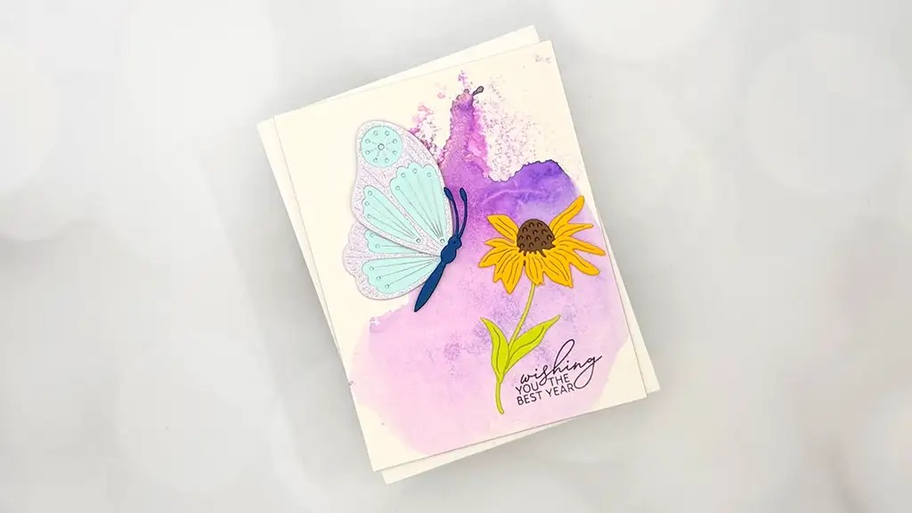 A stunning card for Jan 26 Club Kit, featuring a blue butterfly, a yellow flower, and a purple watercolor background with the text “Wishing you the best year”—perfect inspiration for your card making projects.