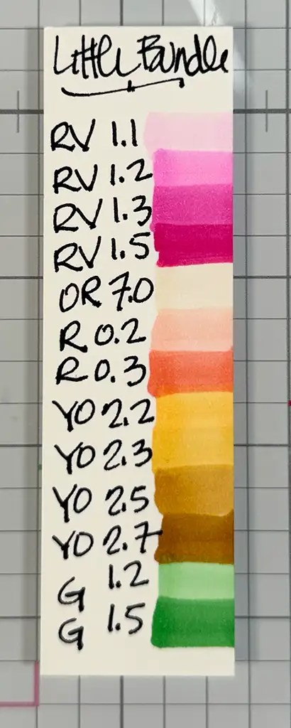 A color swatch card labeled "Little Bundle" shows vertical color strips with handwritten codes and numbers beside each, ranging from pinks and oranges to yellows and greens.
