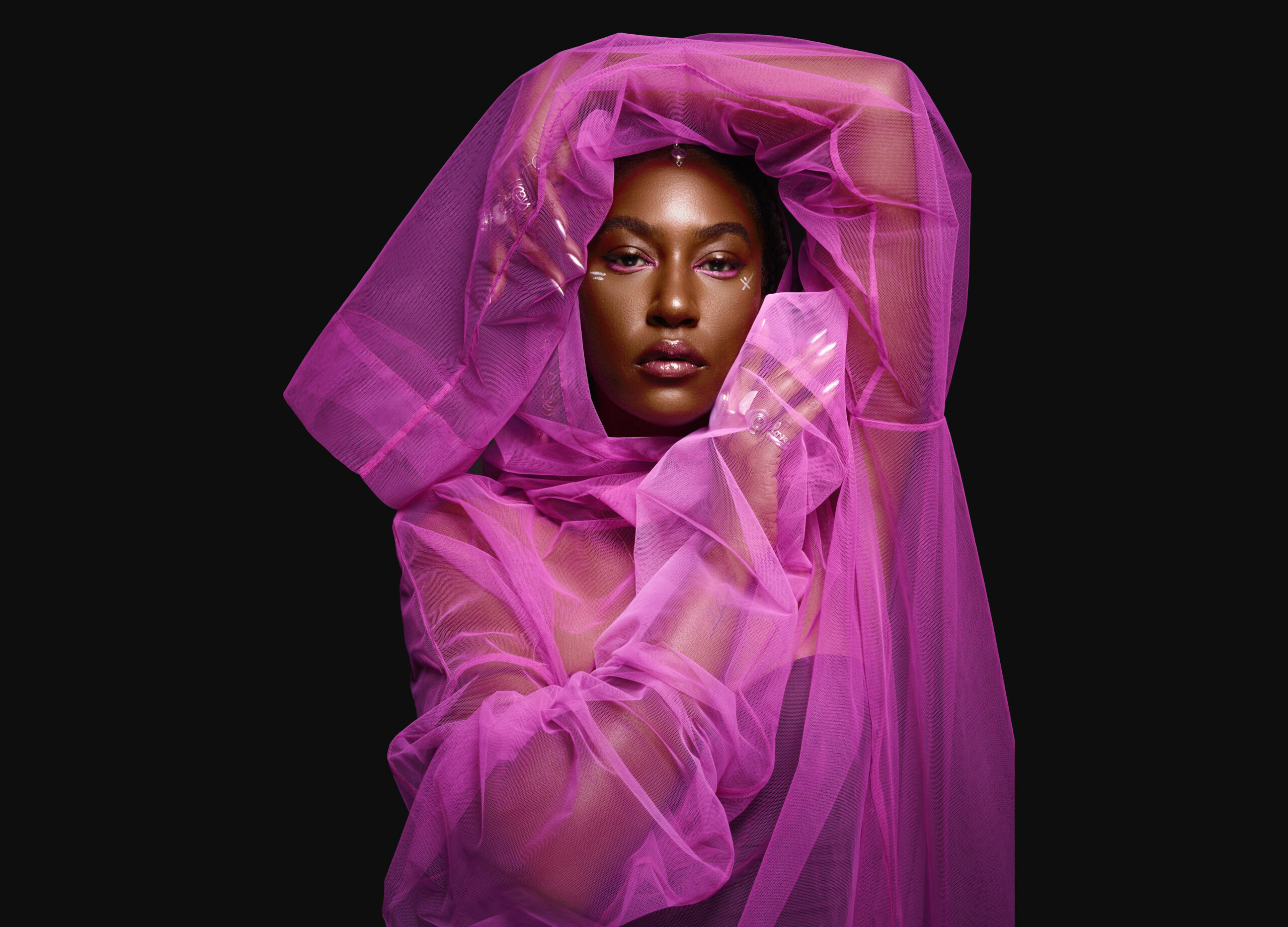 Dominique Fils-Aime draped in light purple fabric with a black background