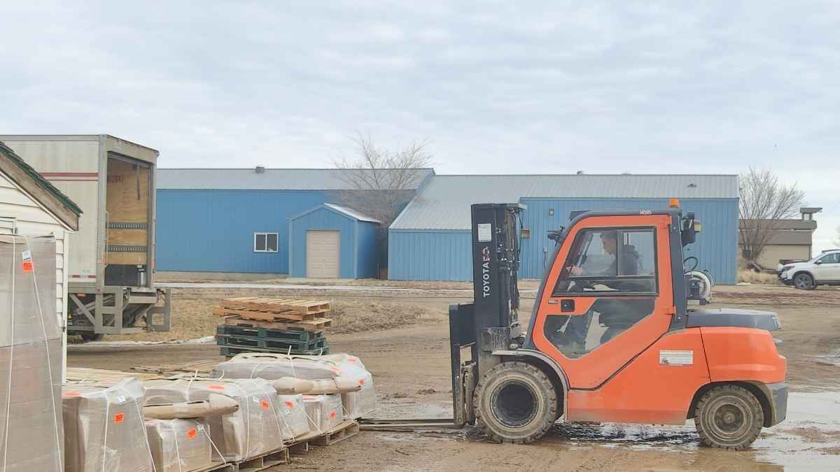 An orange forklift preparing to pick up a skid of cabinet doors. Cutting Edge ships cabinet doors in Abbotsford.