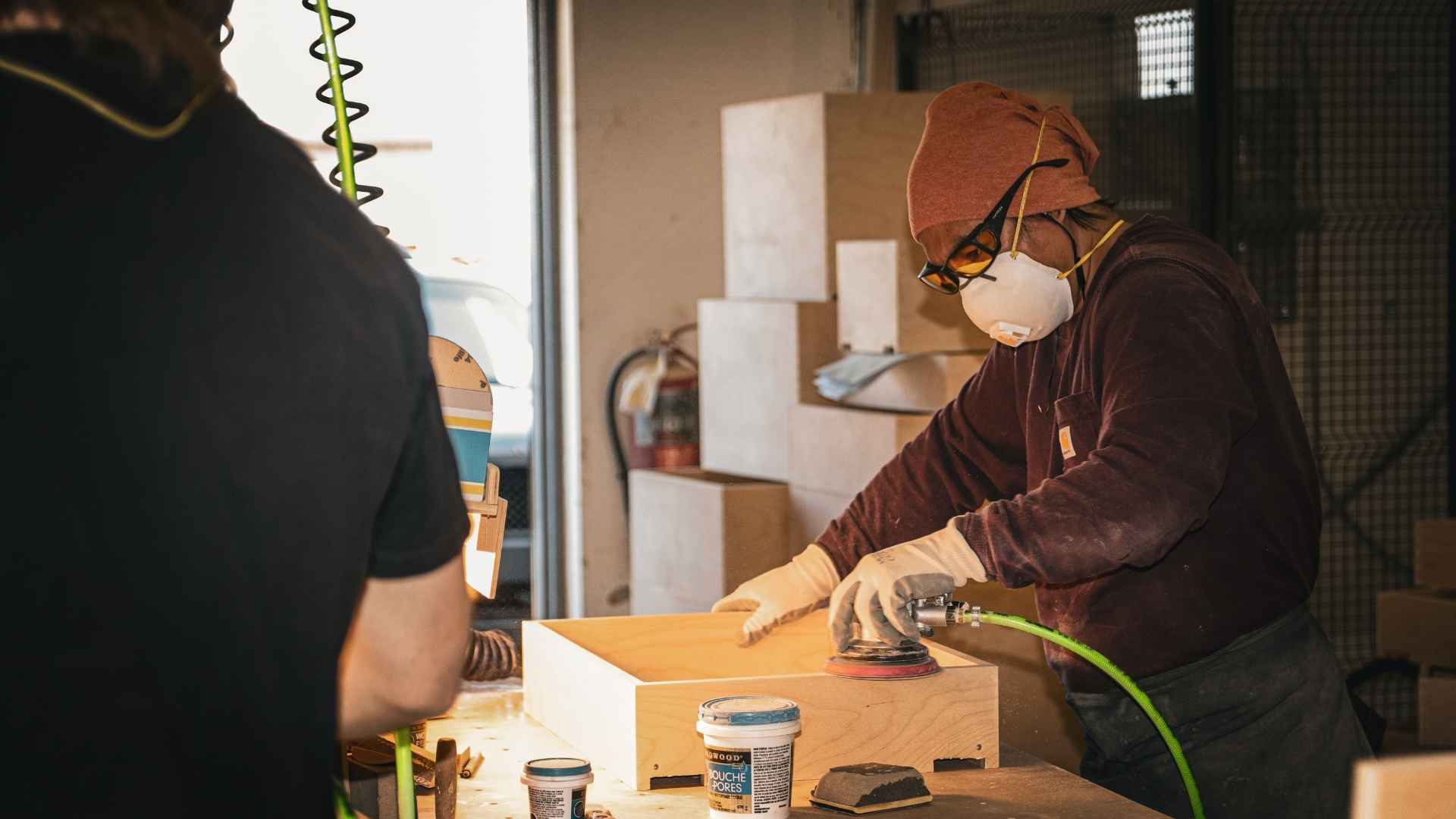 A Cutting Edge employee sanding a drawer box. Cutting Edge offers stepped rabbet drawer boxes, a more economical drawer box option.