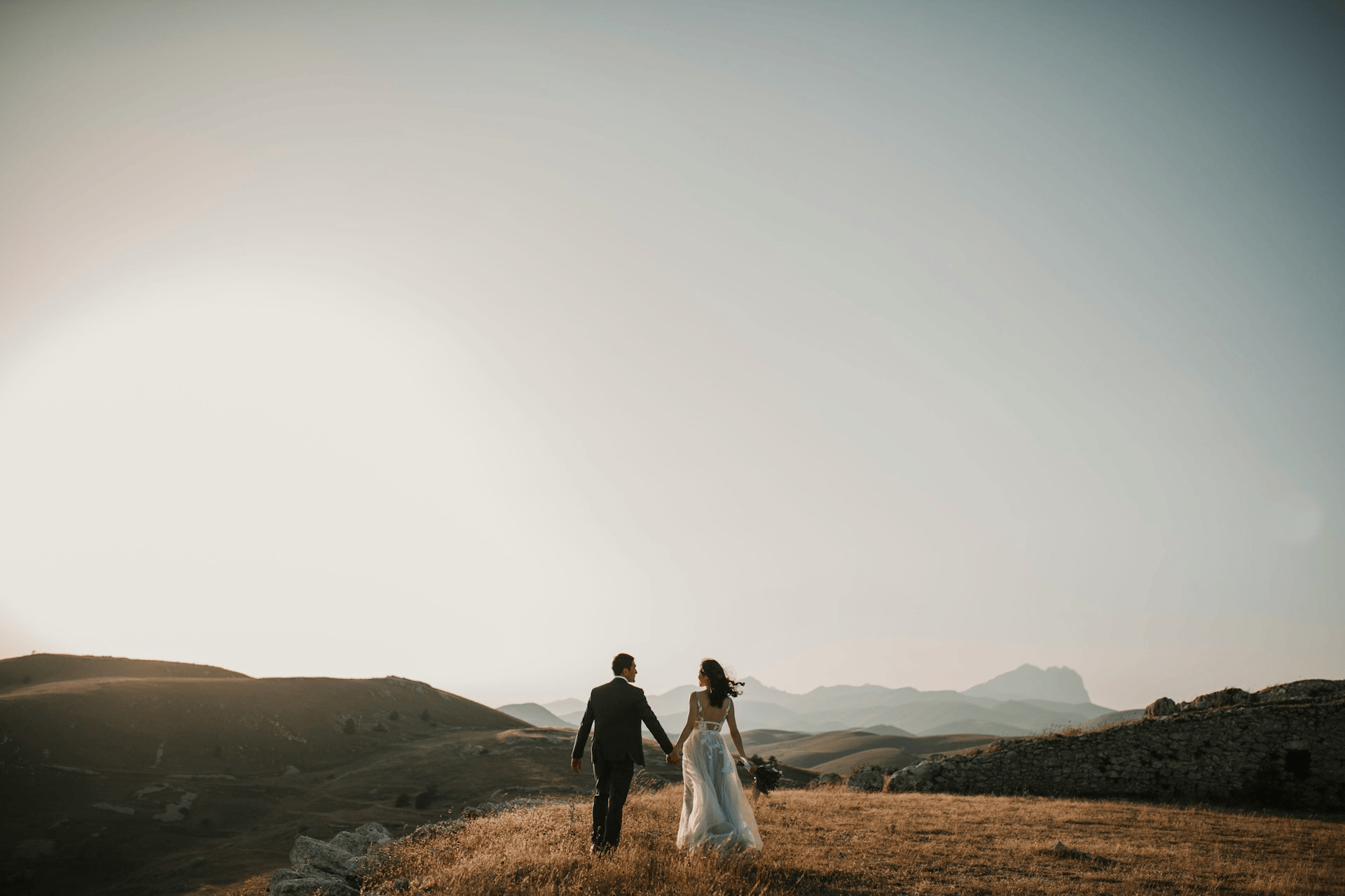 Married couple walking across a hillside at sunset, illustrating decentering your husband