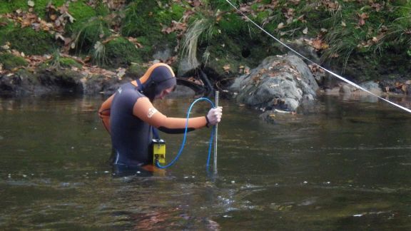 Loïc en combinaison prend des mesures de courant de la rivière