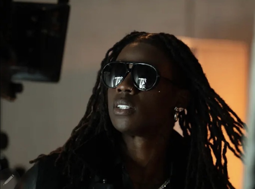A still from Rema's cinematic teaser for the single 'TEA,' featuring bold fashion and dramatic lighting.