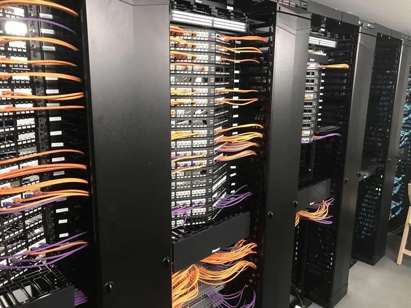 Patchkasten en Racks voor koper en glasvezel naast elkaar. De kabels zijn netjes georganiseerd en gelabeled.