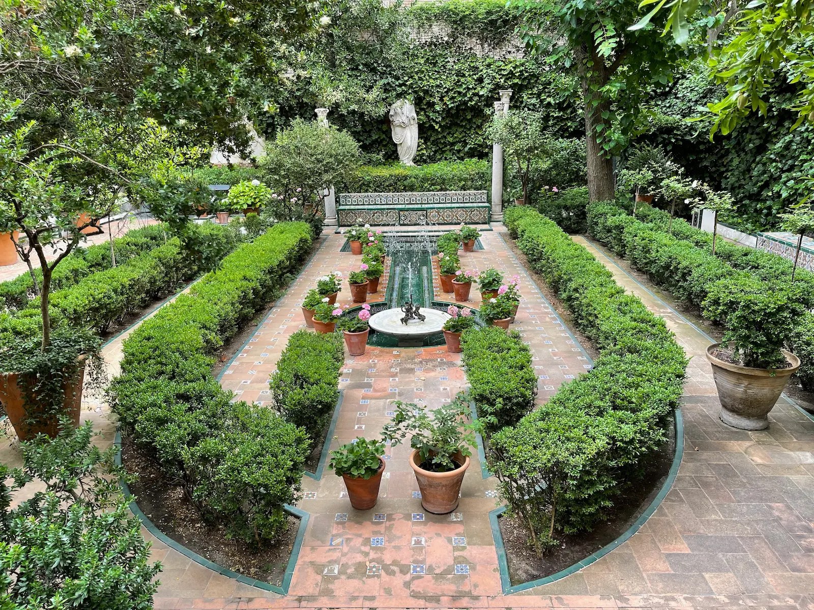 Interior courtyard garden at the Sorolla Museum, with lush greenery, fountains, and tiled walkways. This alt text was generated by AI.