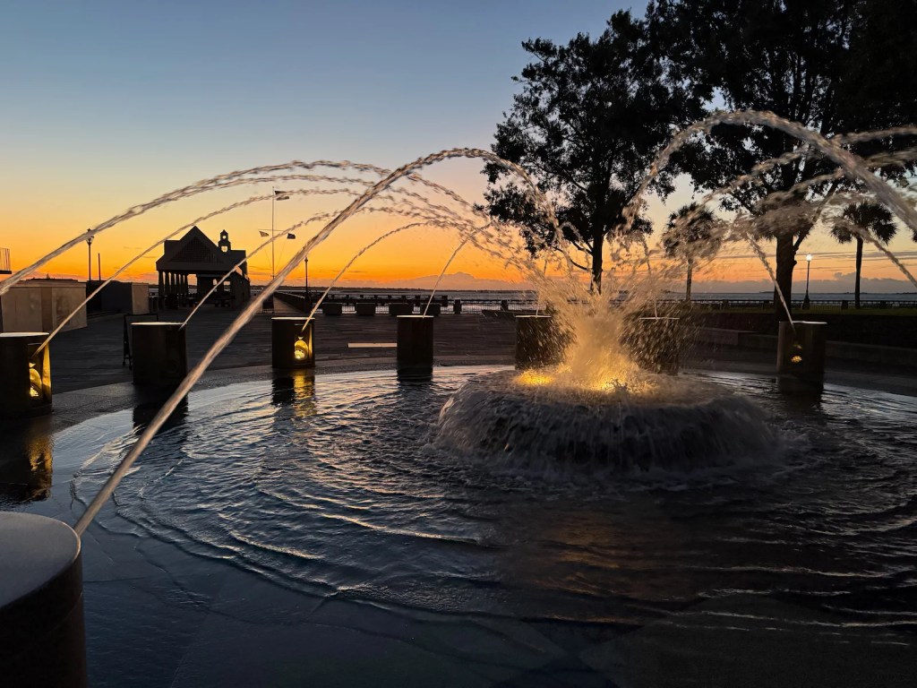 Arched jets of water spraying from a fountain at sunrise.