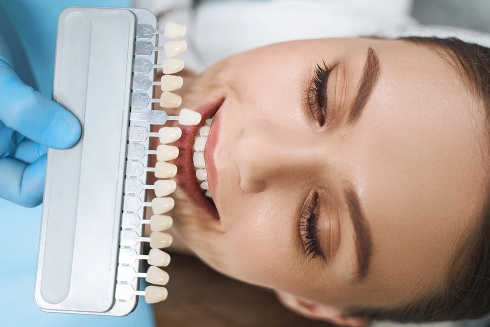 A dentist prepares for a cosmetic dentistry procedure on a young woman patient.