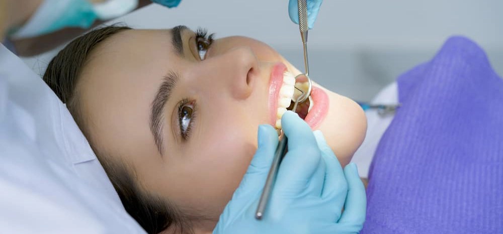 An oral cancer screening performed by a dentist on a female patient.