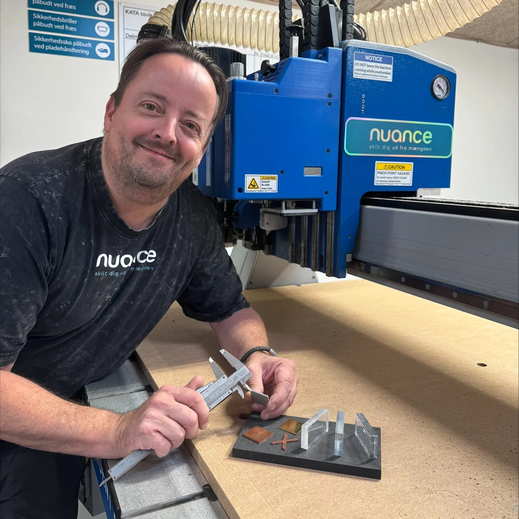 Thomas Jensen fra Nuance Skilte ved CNC-fræseren med skydelære og prøveemner i forskellige materialer.