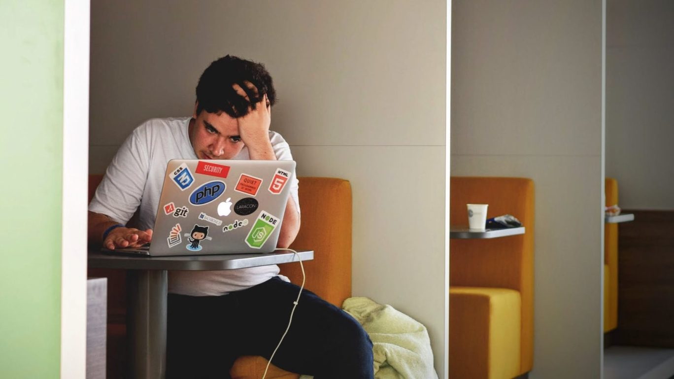 man in white shirt using macbook pro