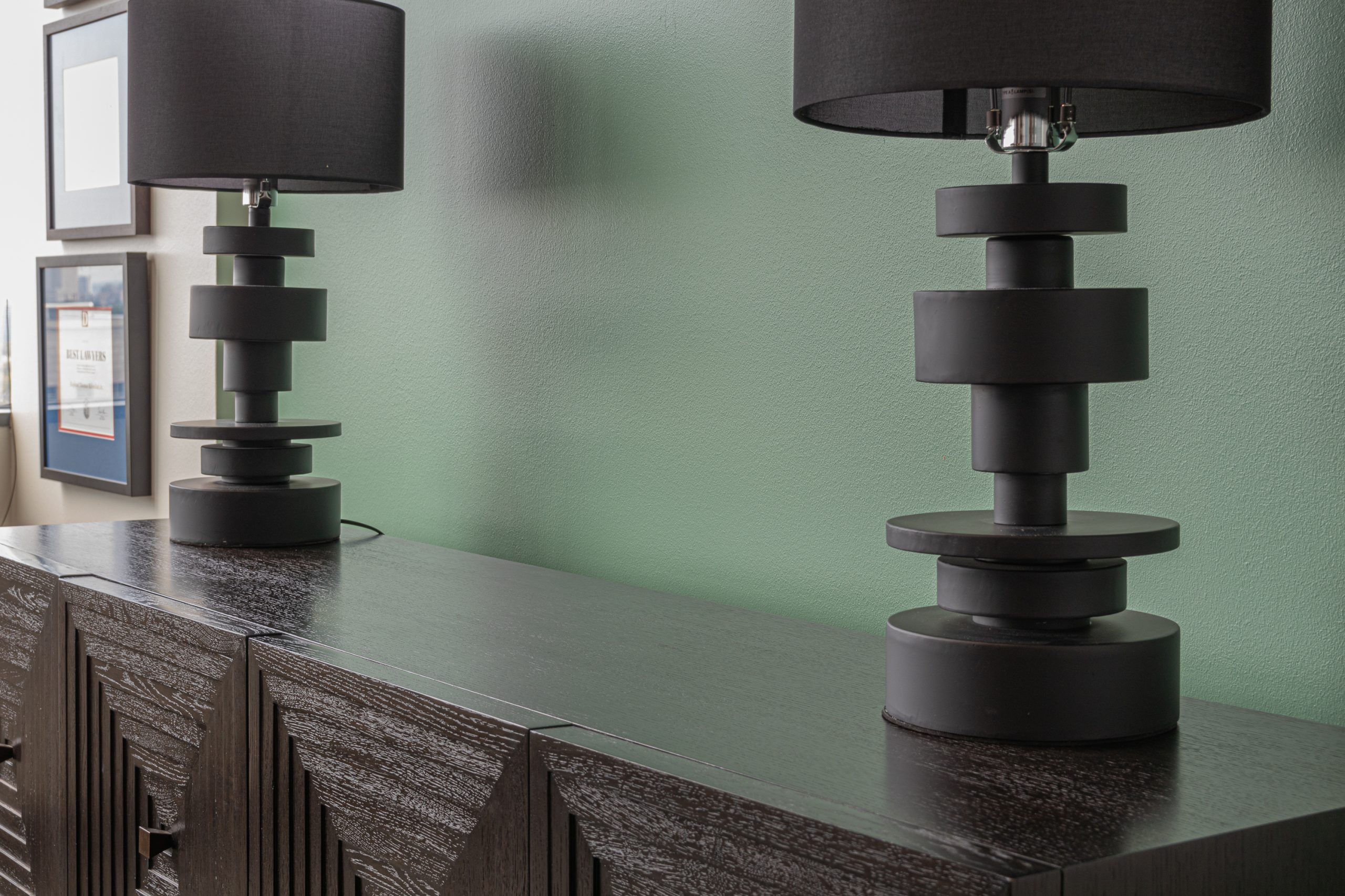 Modern black table lamps on a wooden credenza