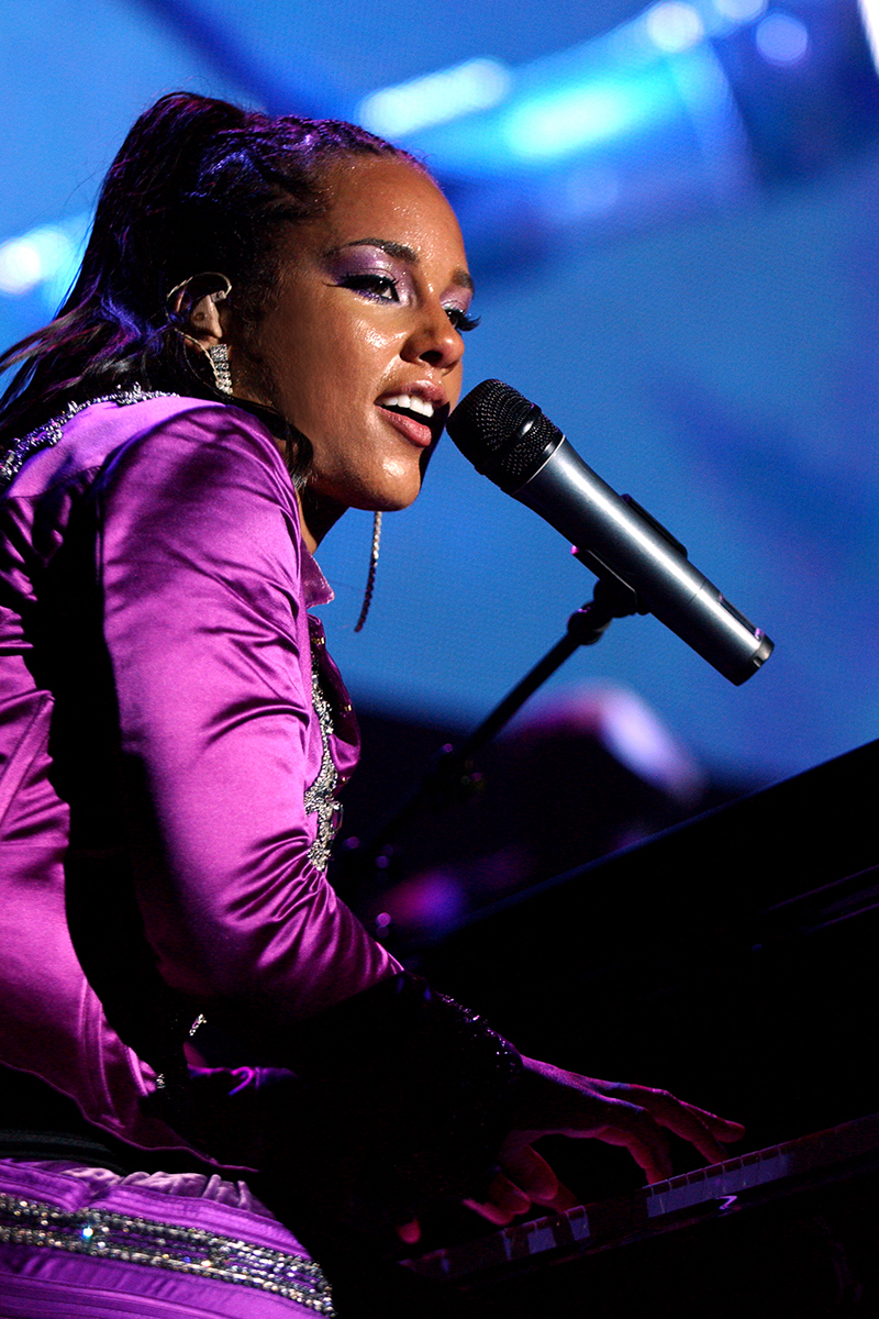 Alicia Keys en concert au Zénith de Paris, jouant au piano et chantant au micro, tenue violette éclatante.