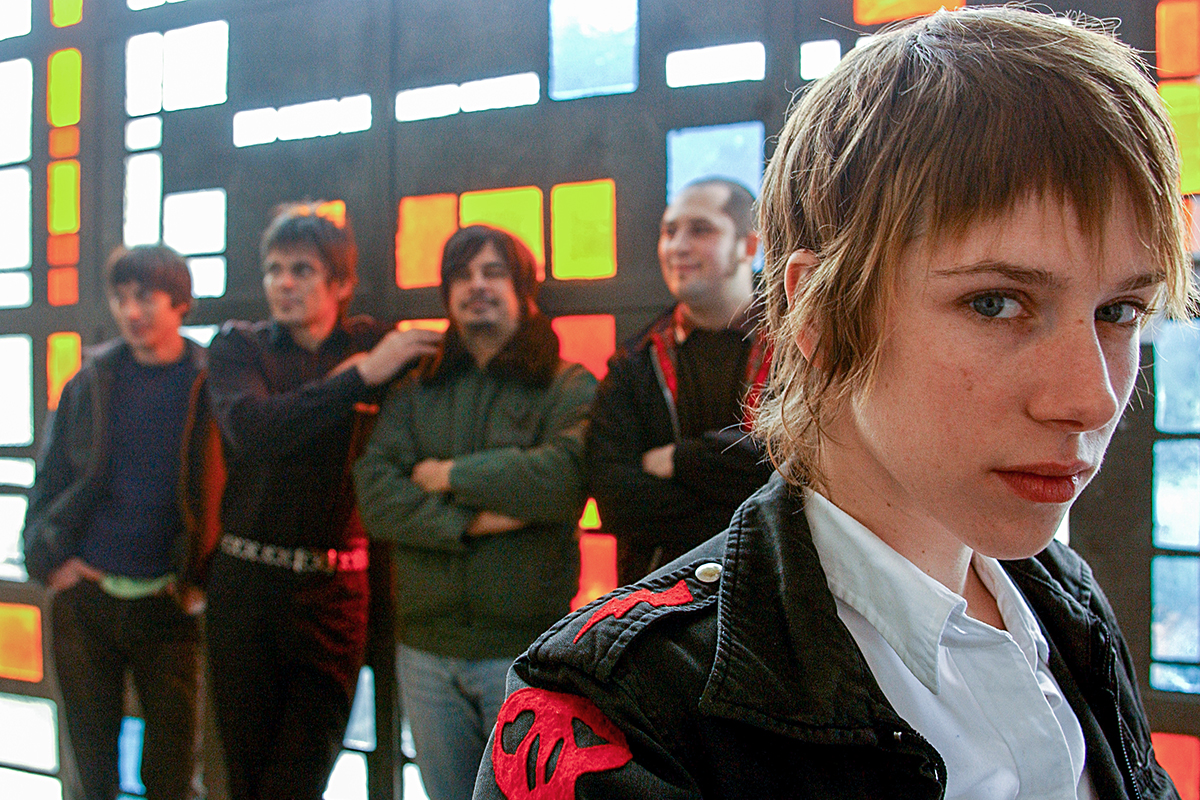 Portrait du groupe AS Dragon avec Natacha Le Jeune au premier plan, devant un mur de vitraux colorés
