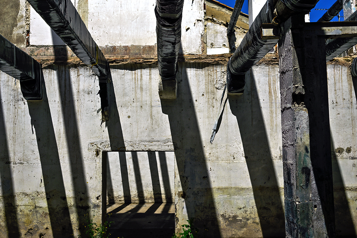 Jeu de lumière dans un entrepôt en rénovation à Béziers, avec des motifs géométriques projetés par des poutres.