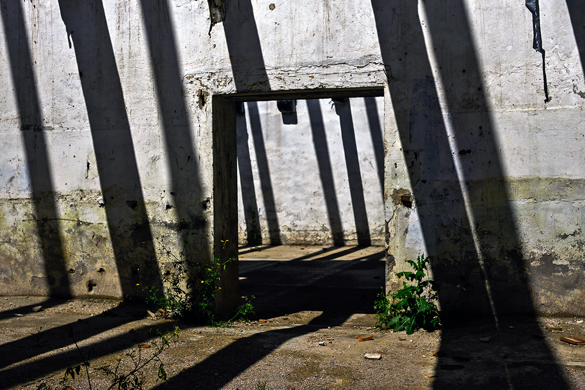 Jeu de lumière dans un entrepôt en rénovation à Béziers, avec des motifs géométriques projetés par des poutres.