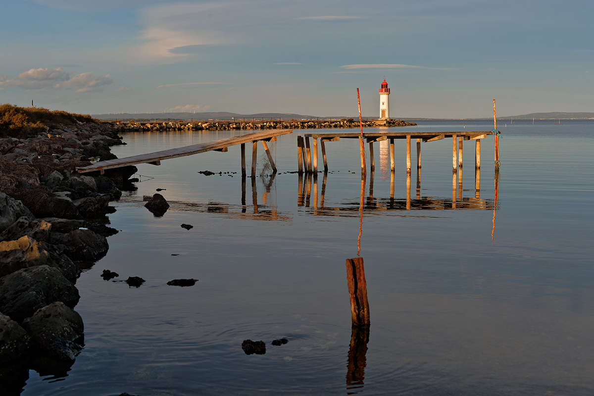 Phare de la Pointe des Onglous à Marseillan avec un ponton en bois s'avançant dans l'eau.
