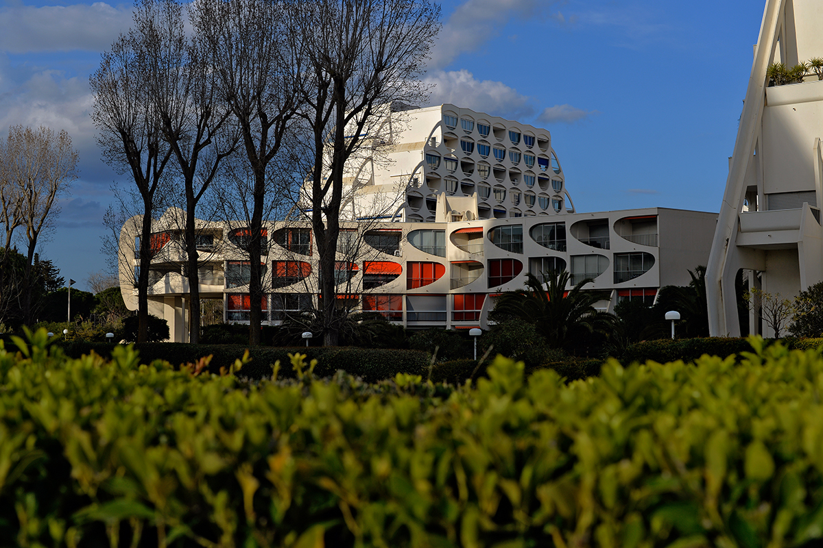 Bâtiment moderne à La Grande-Motte avec une architecture futuriste et des arbres en arrière-plan.