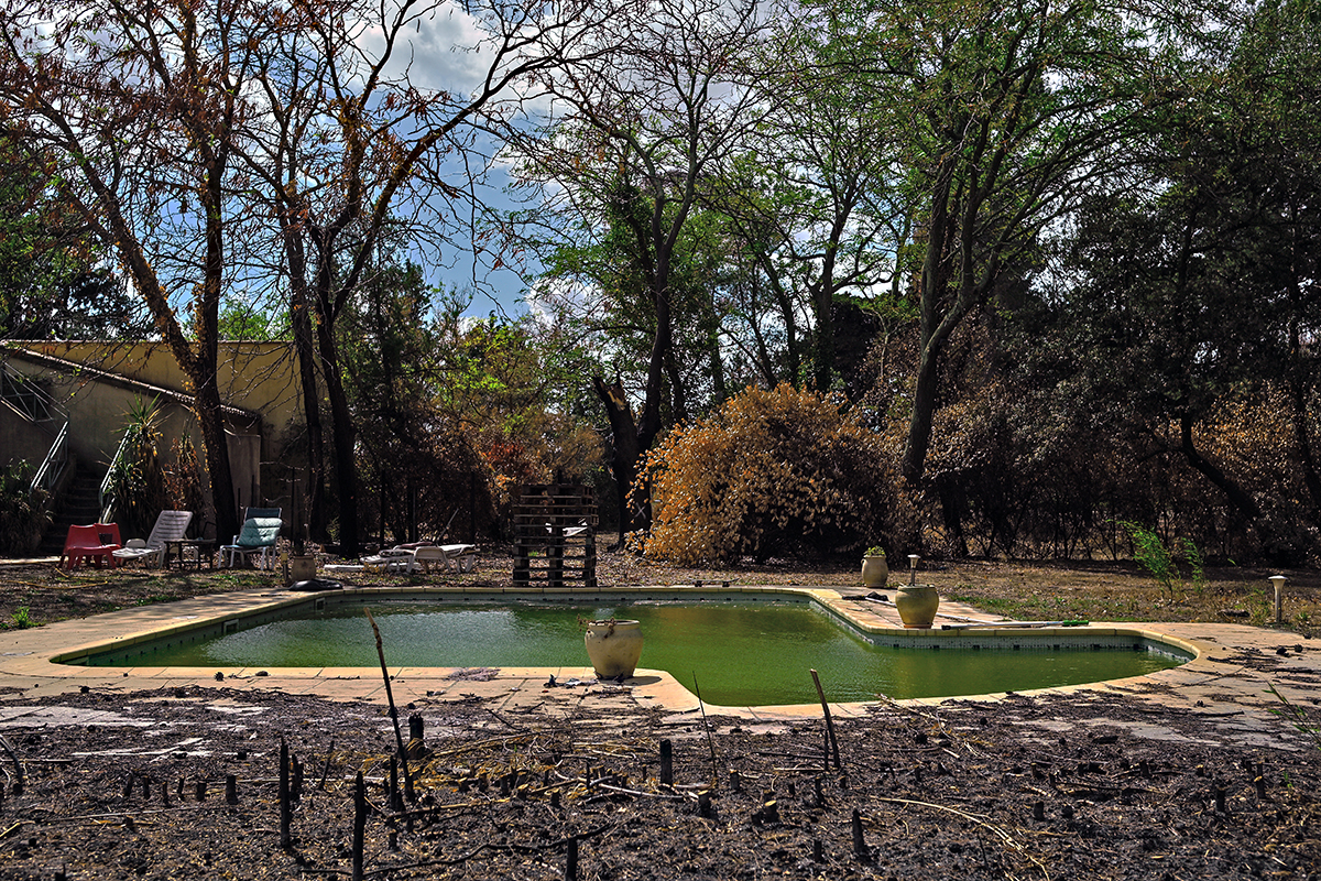 Habitat rural impacté par le feu, vestiges et ruines visibles