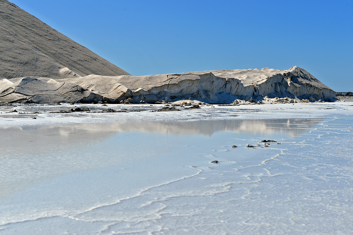 Paysage des Salins de Giraud avec des montagnes de sel et des bassins de saumure sous un ciel bleu.
