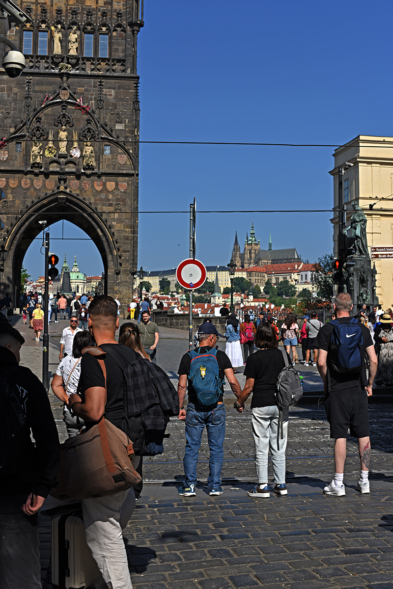 Touristes marchant sur le pont Charles à Prague, avec une vue sur le château de Prague en arrière-plan.