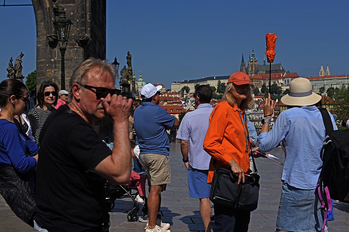 Touristes photographiant et admirant la vue depuis le pont Charles à Prague, avec le château de Prague en arrière-plan.