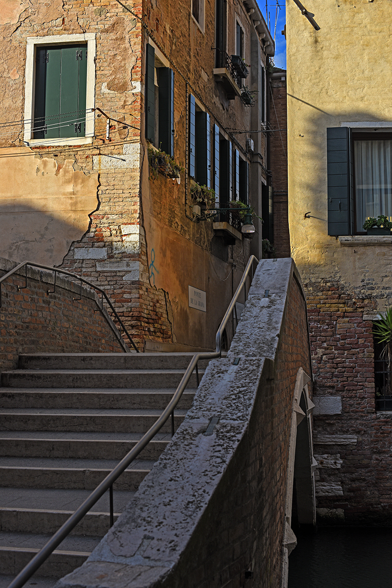 Ruelle étroite de Venise avec des escaliers et des bâtiments colorés.