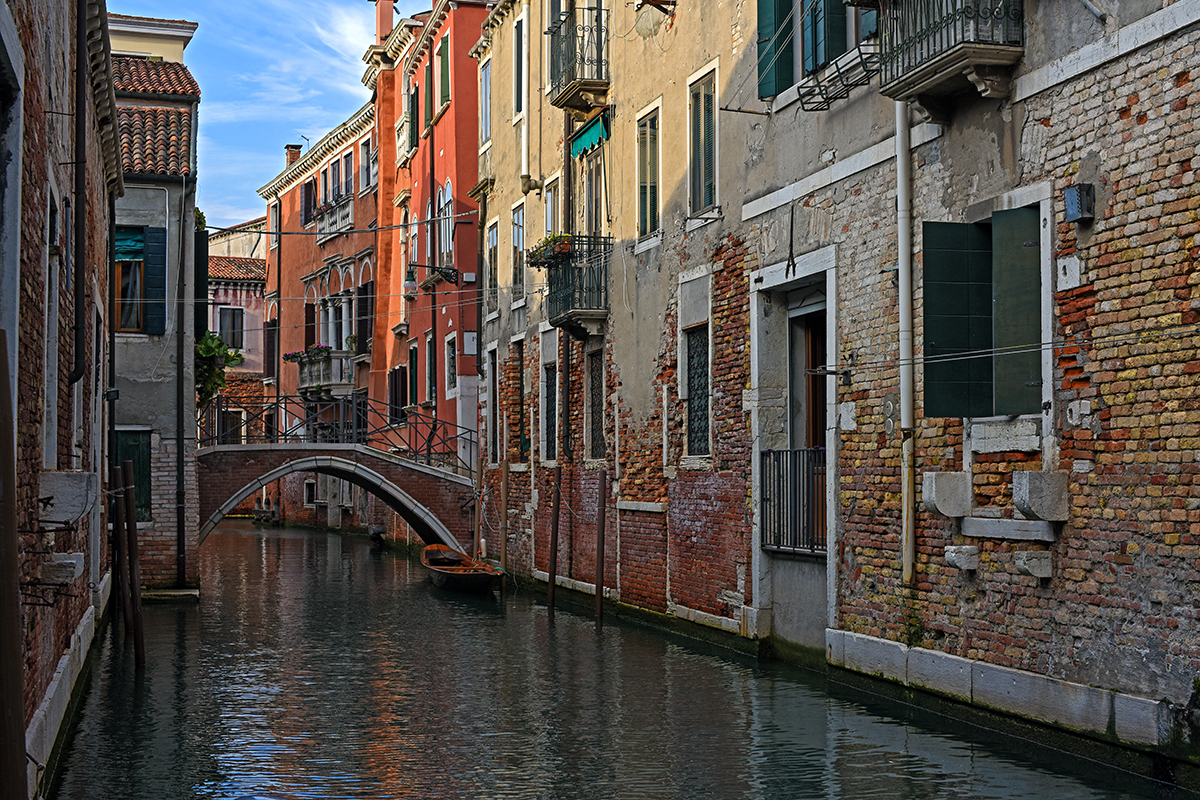 Canal de Venise avec un petit pont en pierre et des bâtiments colorés le long des rives.