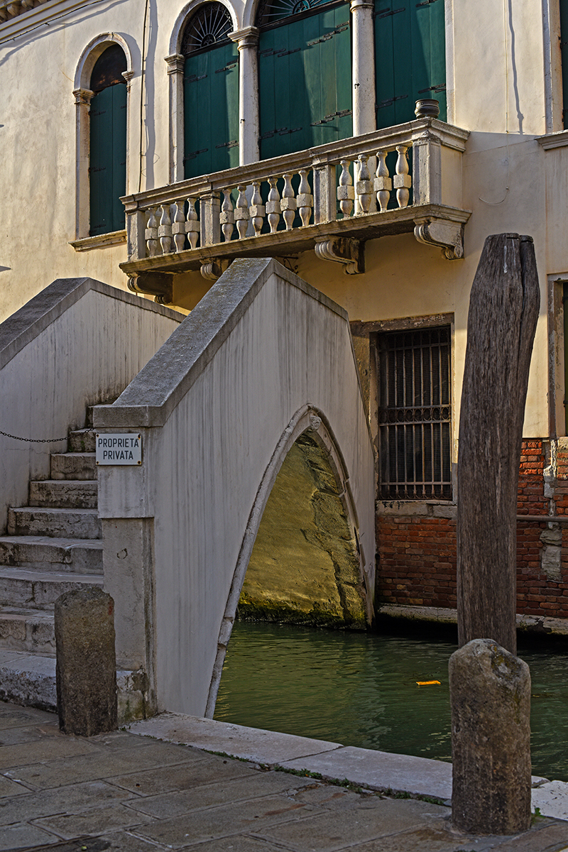 Pont privé à Venise avec un bâtiment aux volets verts et un canal en dessous