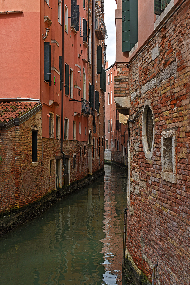 Canal étroit de Venise bordé de bâtiments en brique et de façades colorées