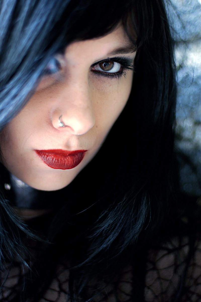 Gros plan sur Candice Clot, regard perçant, rouge à lèvres carmin et cheveux noirs.