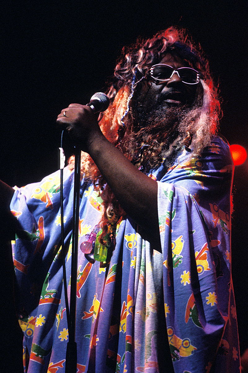 George Clinton sur scène au Zénith de Paris, vêtu d’une tunique colorée et tenant un micro
