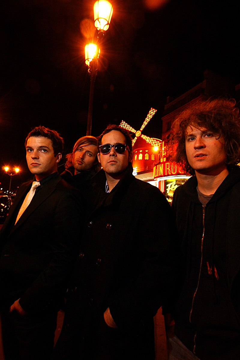 Le groupe The Killers posé de nuit devant le Moulin Rouge à Paris