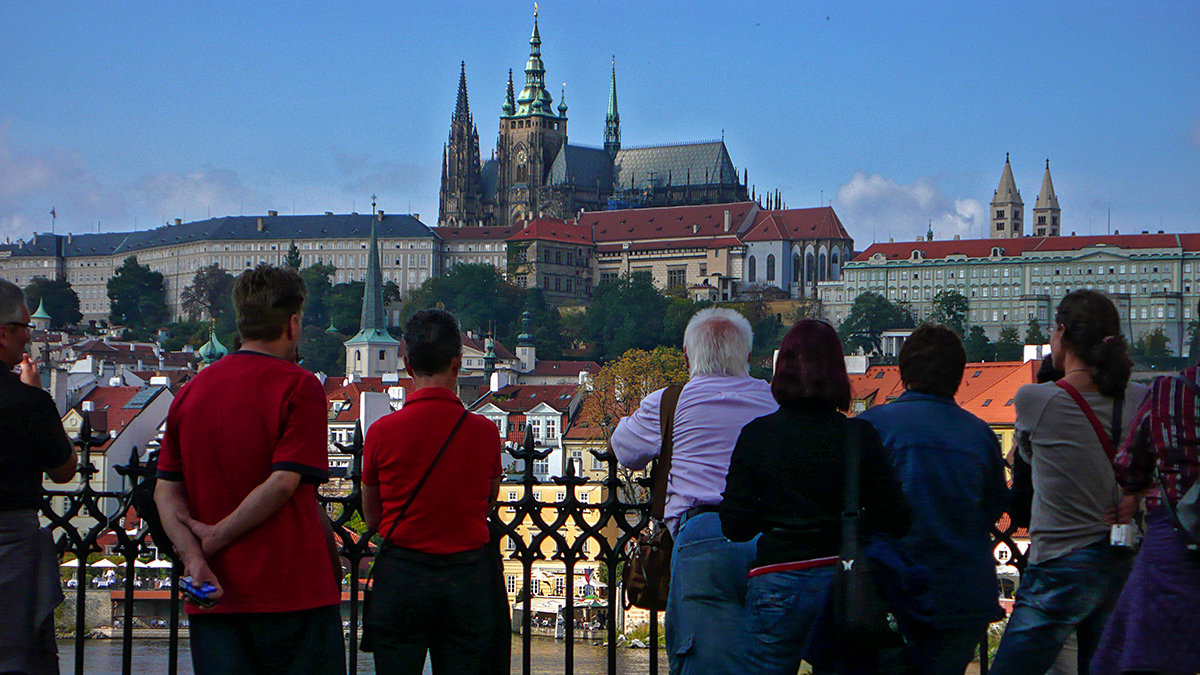 Touristes admirant le château de Prague en 2010, avec une vue sur les toits historiques de la ville.