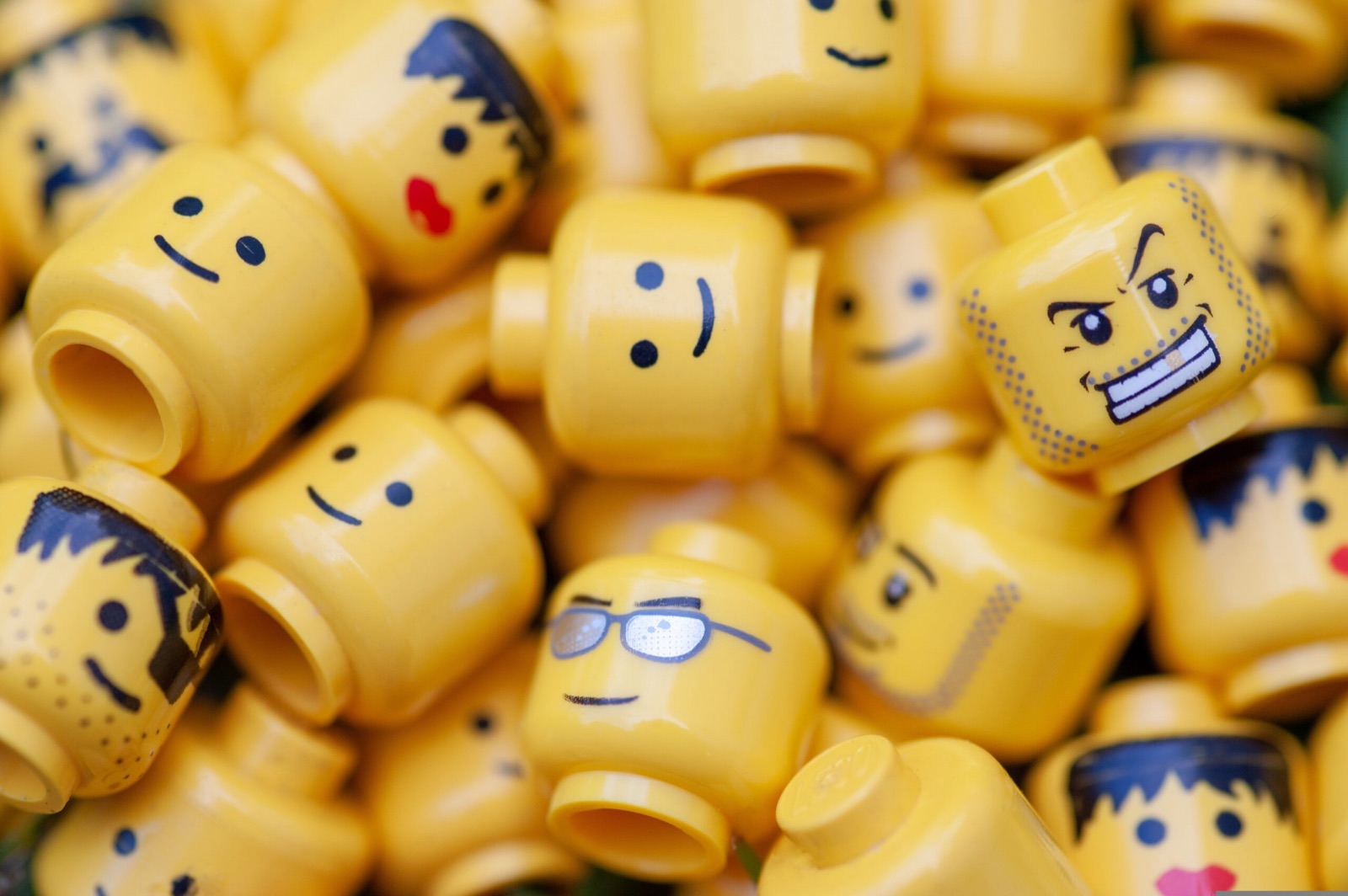 A pile of yellow LEGO minifigure heads with different faces