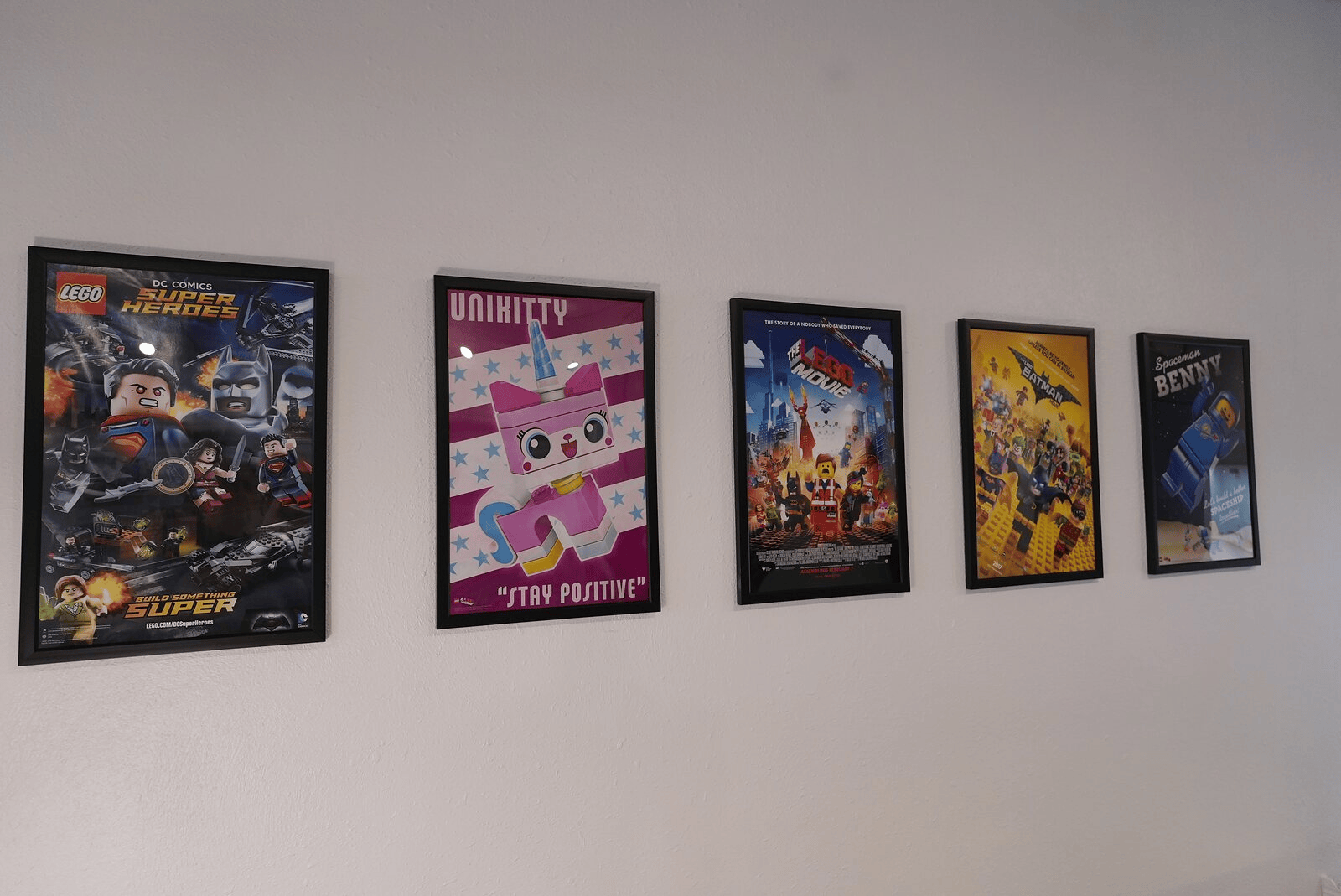 Framed LEGO character and movie posters on the wall at Dapper Bricks