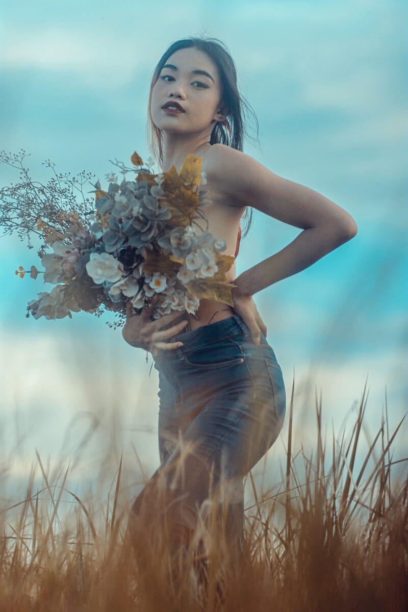 woman in blue denim jeans holding white flowers