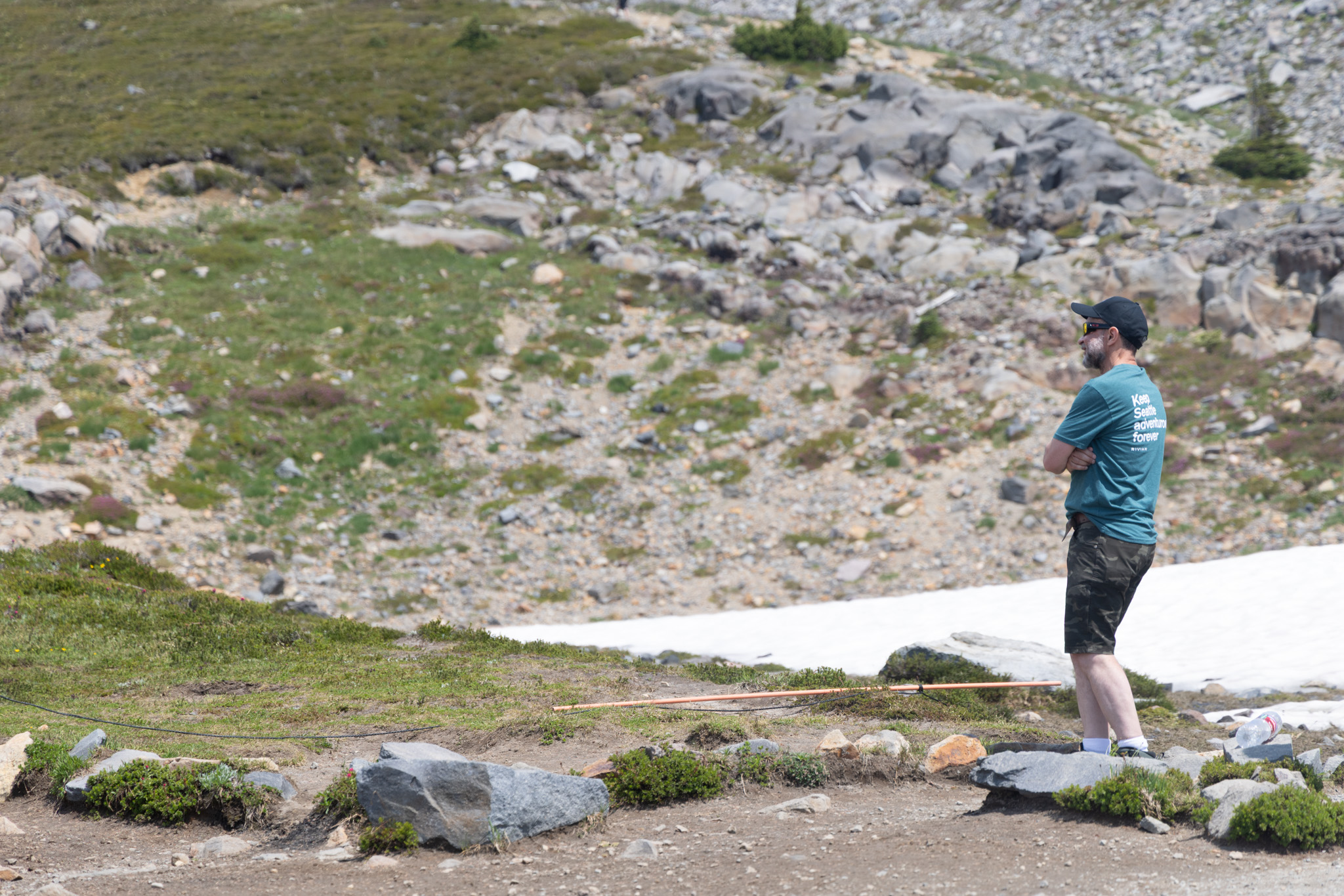 A hiker pausing beside a patch of summer snow