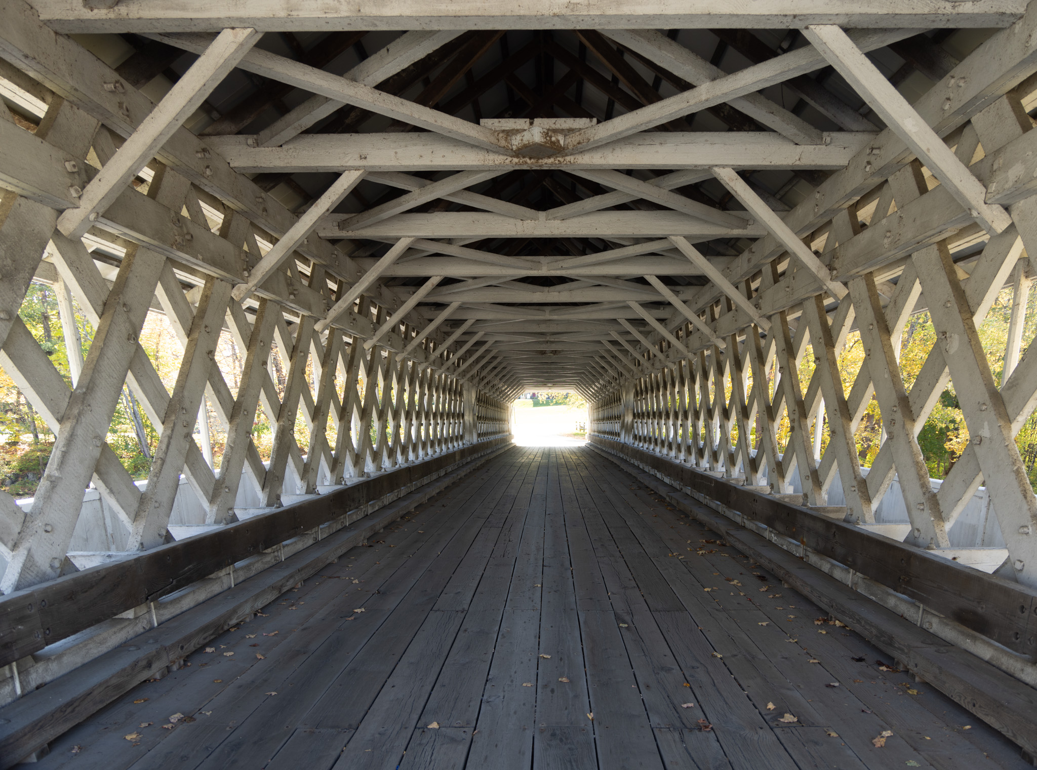 Looking through the inside of a white lattice covered bridge