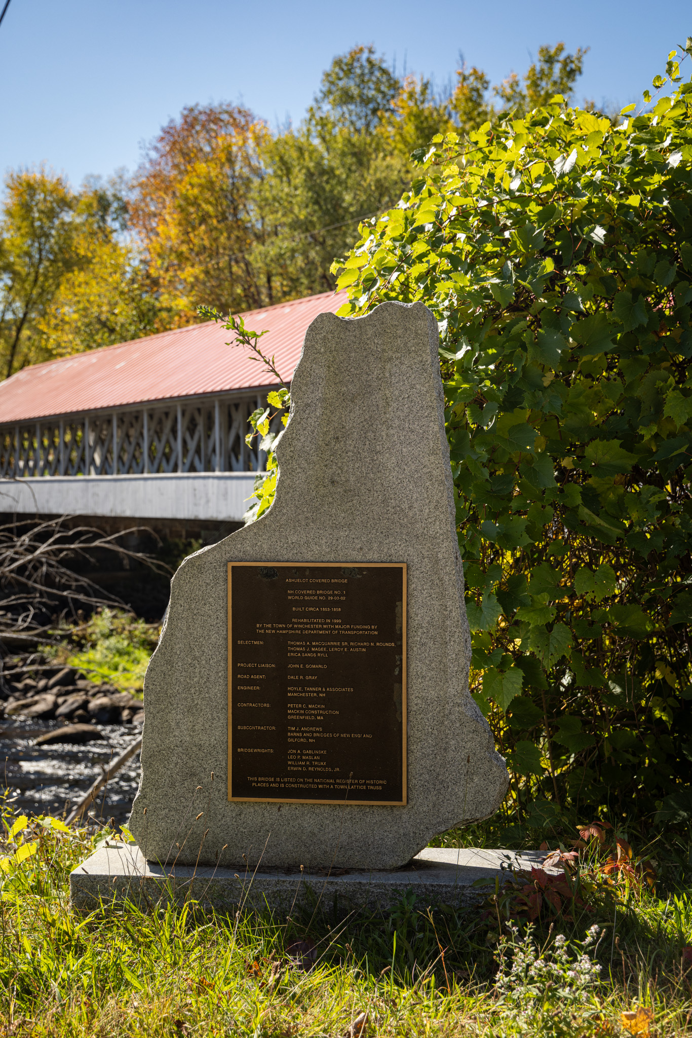 Stone marker with a plaque in front of the Ashuelot Covered Bridge