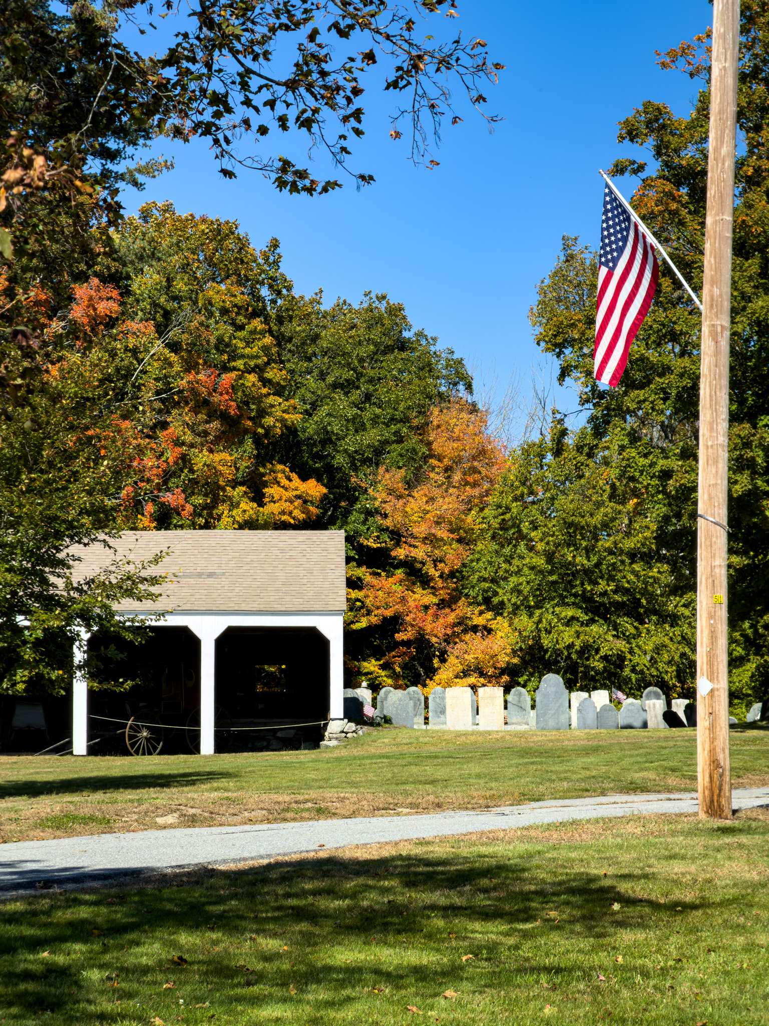 Small white building beside an old cemetery with an American flag in Ashby