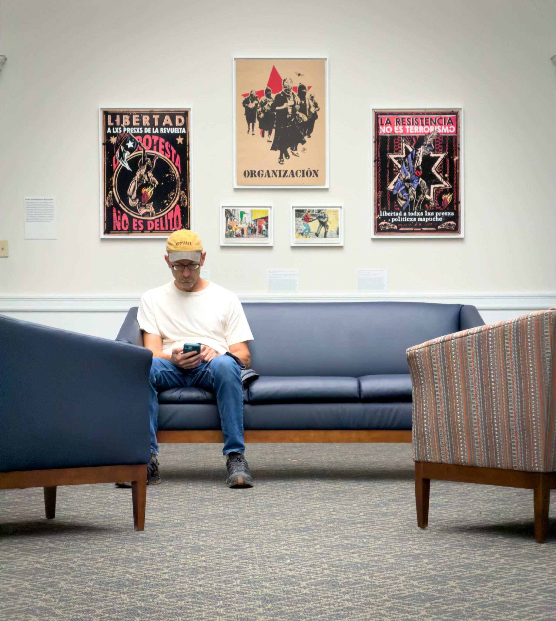 A visitor reading on a couch beneath posters at the RISD Museum