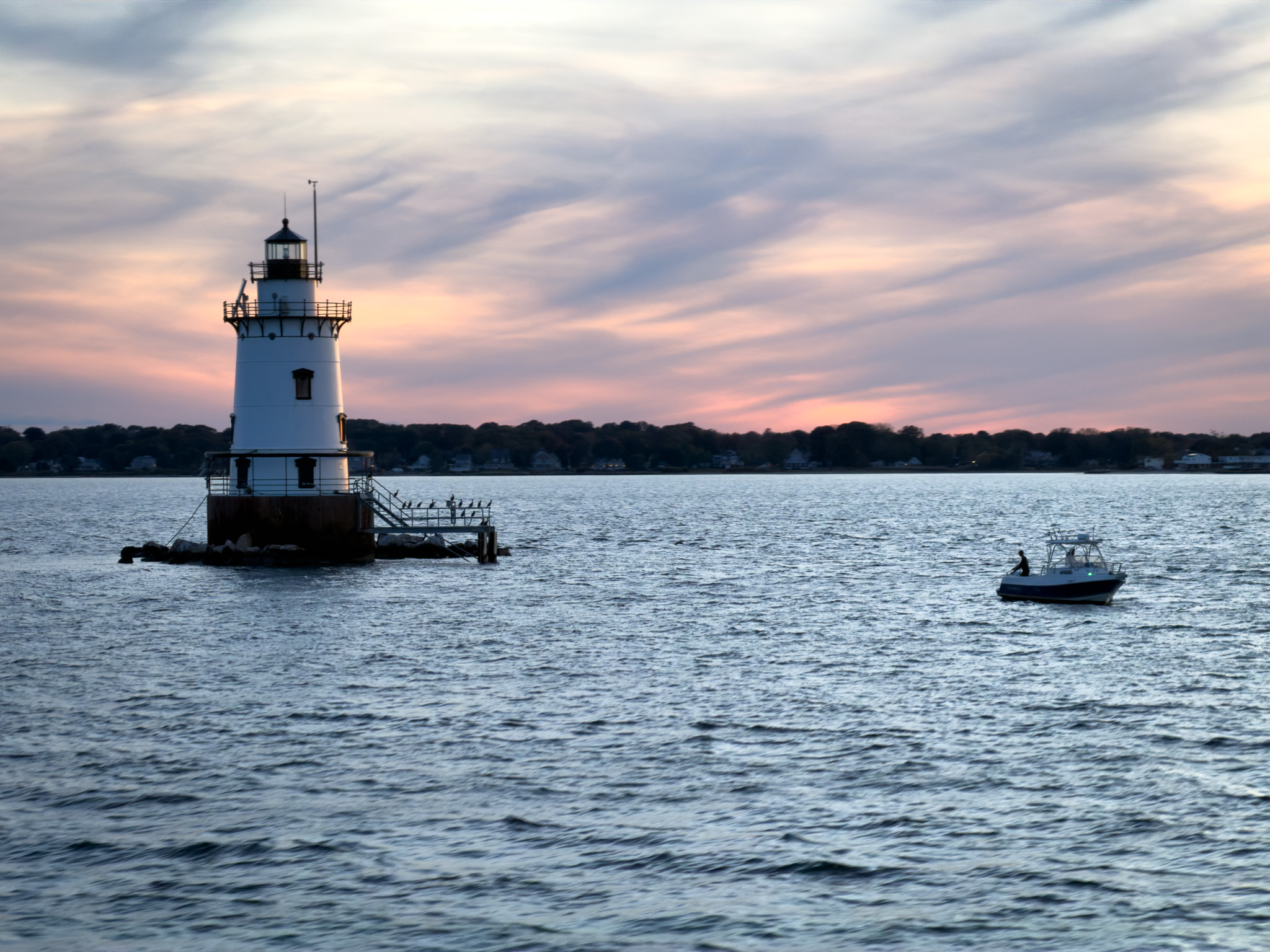 Lighthouse at dusk with a small boat nearby