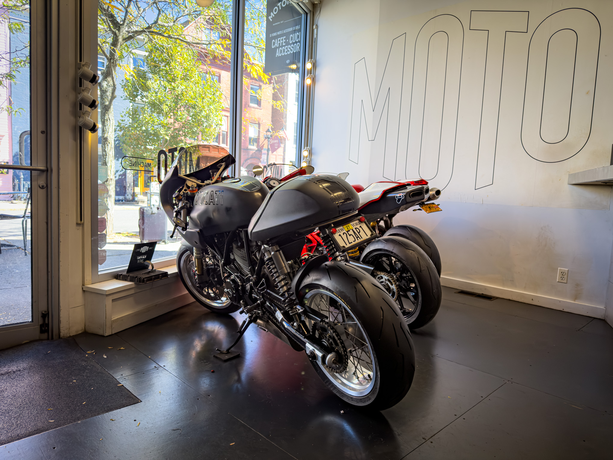 Black sport motorcycle parked inside the shop window with a large MOTO logo on the wall