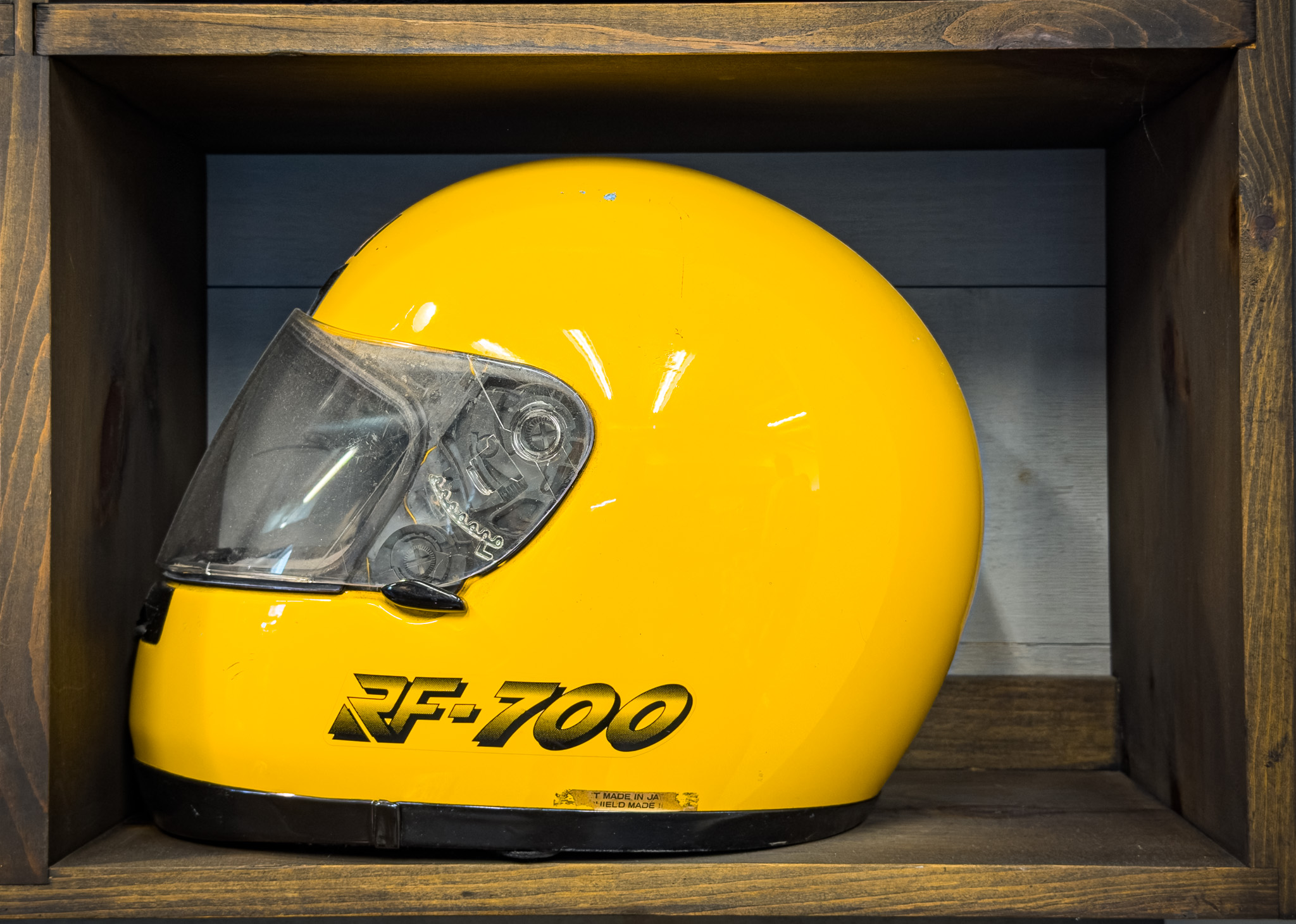 Yellow full-face helmet displayed in a wooden box shelf