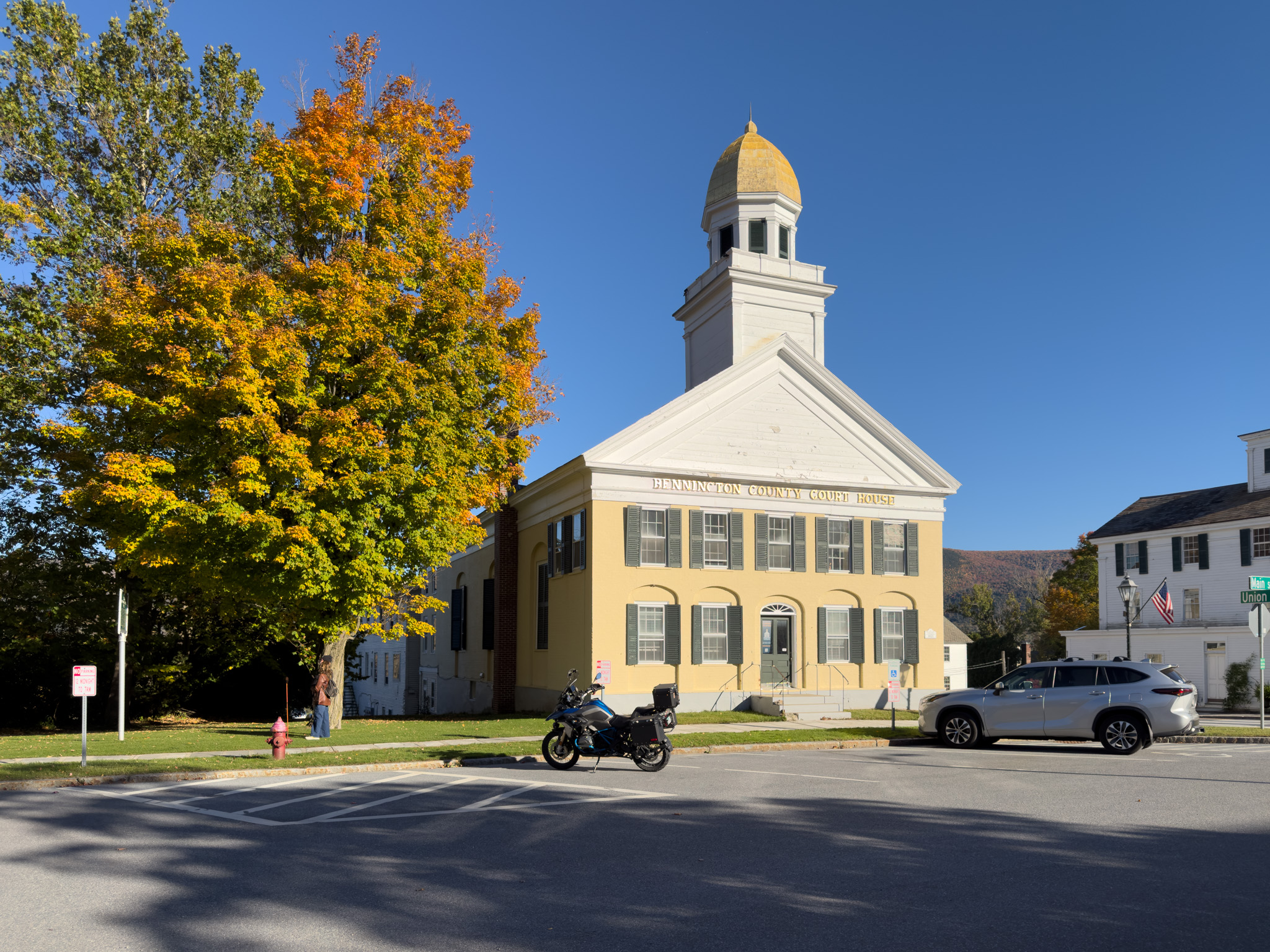Yellow building with a gold cupola behind an orange maple, with the GS parked in front