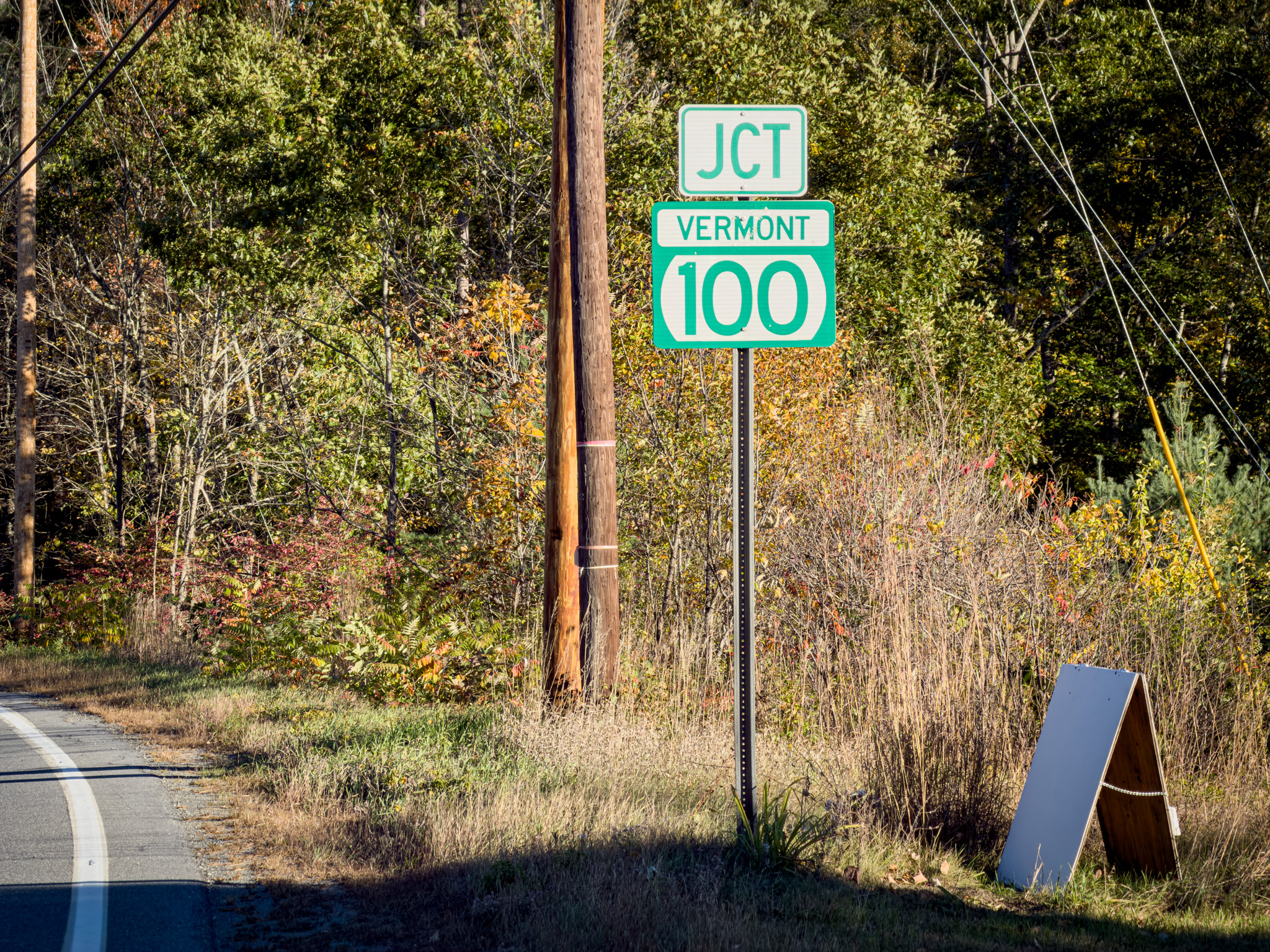 Green JCT Vermont 100 route sign beside the road