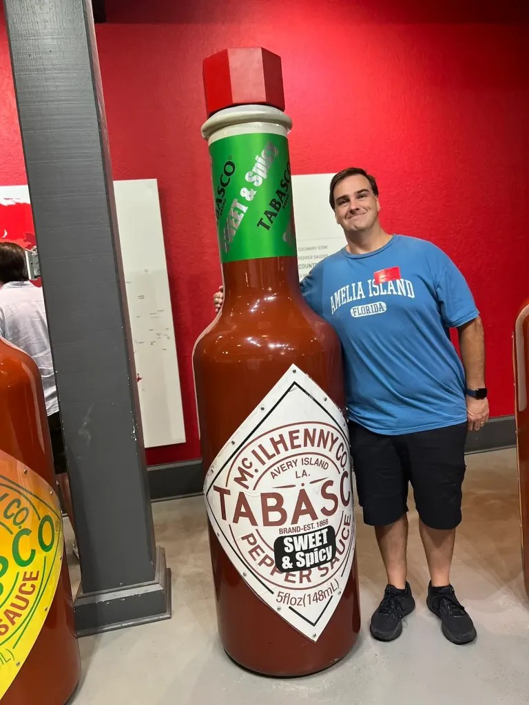 Jason and bottle of giant bottle Tabasco that is taller than he is